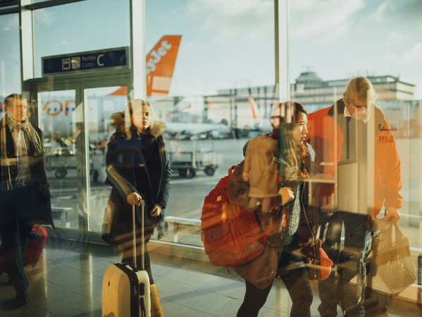 people in reflected in an airport window with planes in the background