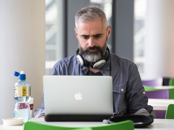 man sitting in a cafeteria looking at his laptop